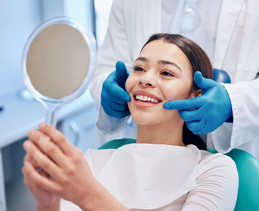 Patient smiling at reflection in handheld mirror
