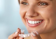 Woman with hazel eyes smiling holding Invisalign