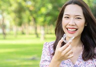 Woman outside smiling holding Invisalign
