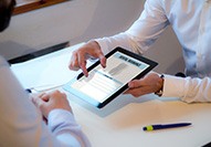 Patient and dentist looking at dental insurance on digital tablet