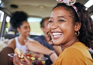 Woman smiling while eating meal with friends in car