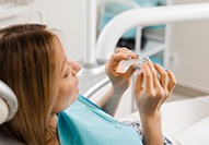 Patient holding clear aligner in treatment chair