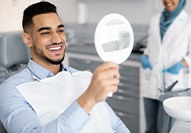 Man smiling at reflection in mirror in treatment chair