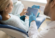 Dentist and patient conversing over electronic tablet