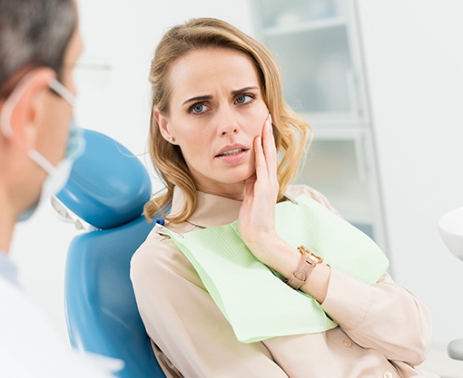 Woman in dental chair holding cheek