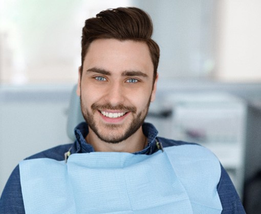 Male dental patient sitting in chair and smiling