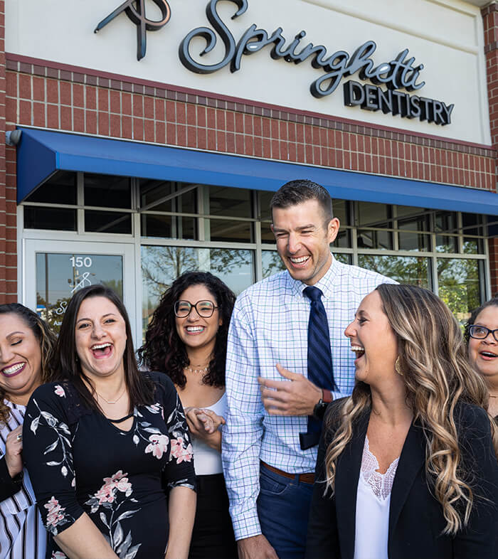 Springhetti Dentistry team laughing in front of dental office