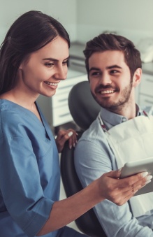 Dental team member talking to man in dental chair