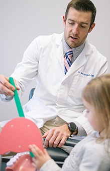Dentist showing a child patient how to brush their teeth