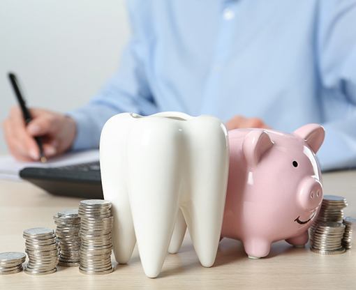 tooth, piggy bank, coins, and calculator 