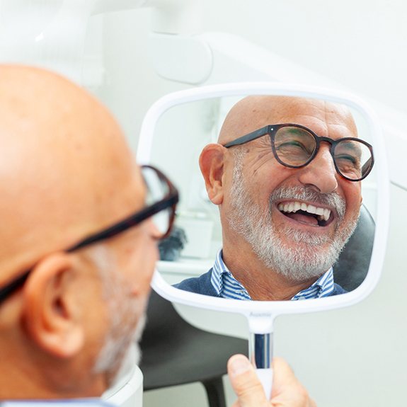 A man smiling at his full mouth restoration results