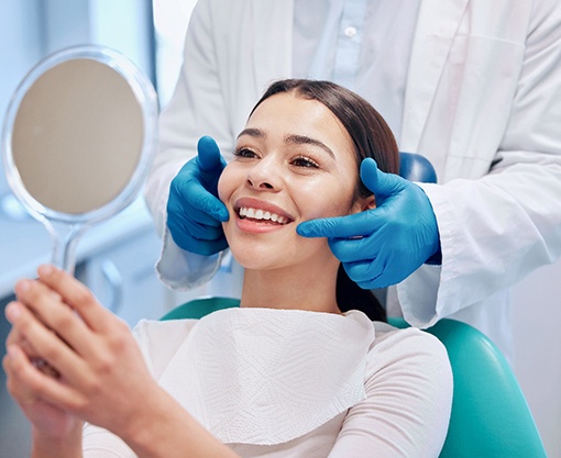 Patient smiling at reflection in handheld mirror