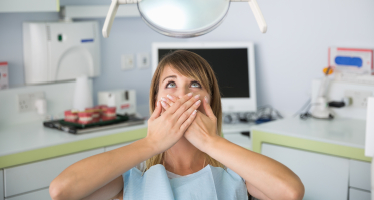 Woman in dental chair covering mouth