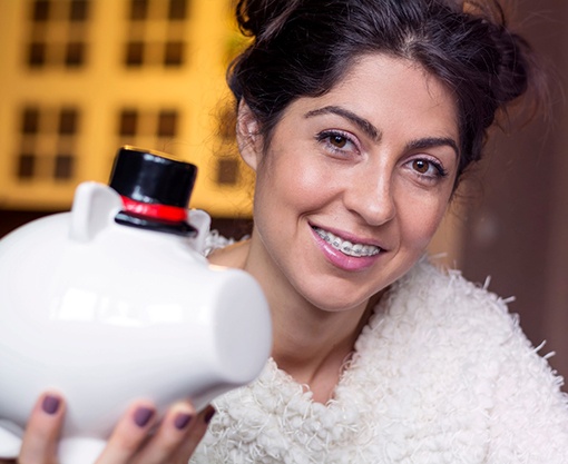 young woman with braces holding a piggy bank