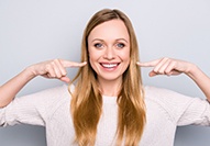 Woman smiling and pointing at her teeth 