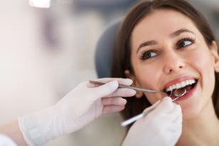 Woman with brown hair getting a checkup from a dentist