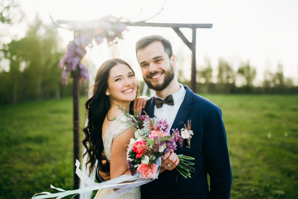 Bride and groom smiling in front of alter outside