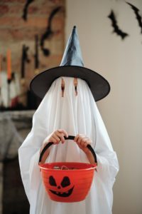 Child dressed up as a ghost holding a candy bucket