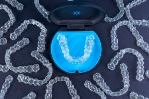 Several Invisalign trays surrounding a case