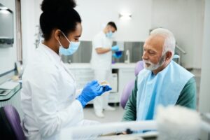 Dentist showing senior patient a set of dentures. 